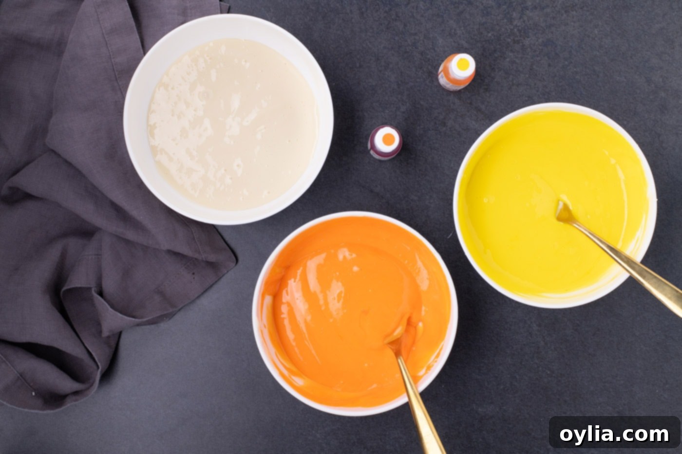 Three bowls of cheesecake filling: yellow, orange, and original cream-colored