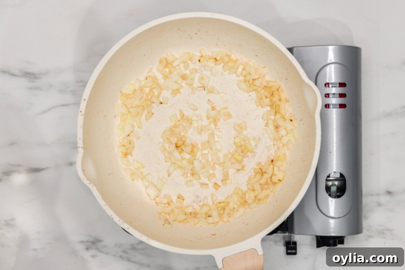 Chopped onions sautéing in a skillet until softened and lightly browned.