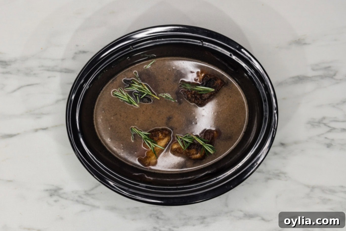 rosemary sprigs on top of crockpot beef short ribs