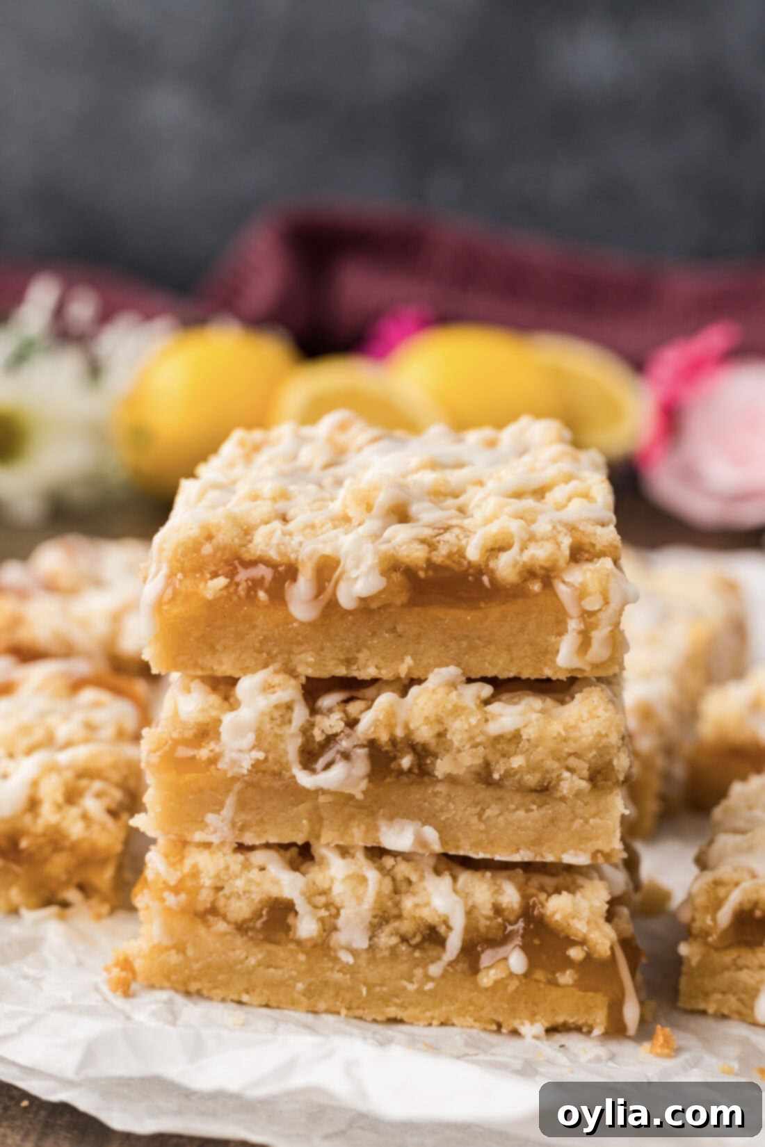 Stack of three Lemon Streusel Squares on a white plate, garnished with fresh lemon zest and mint sprigs.