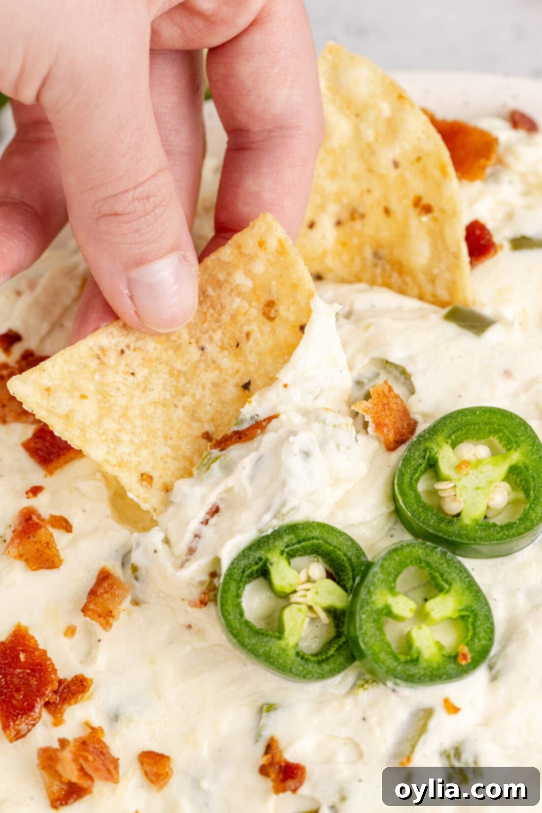 Chip being dipped into a bowl of Crockpot Jalapeno Popper Dip