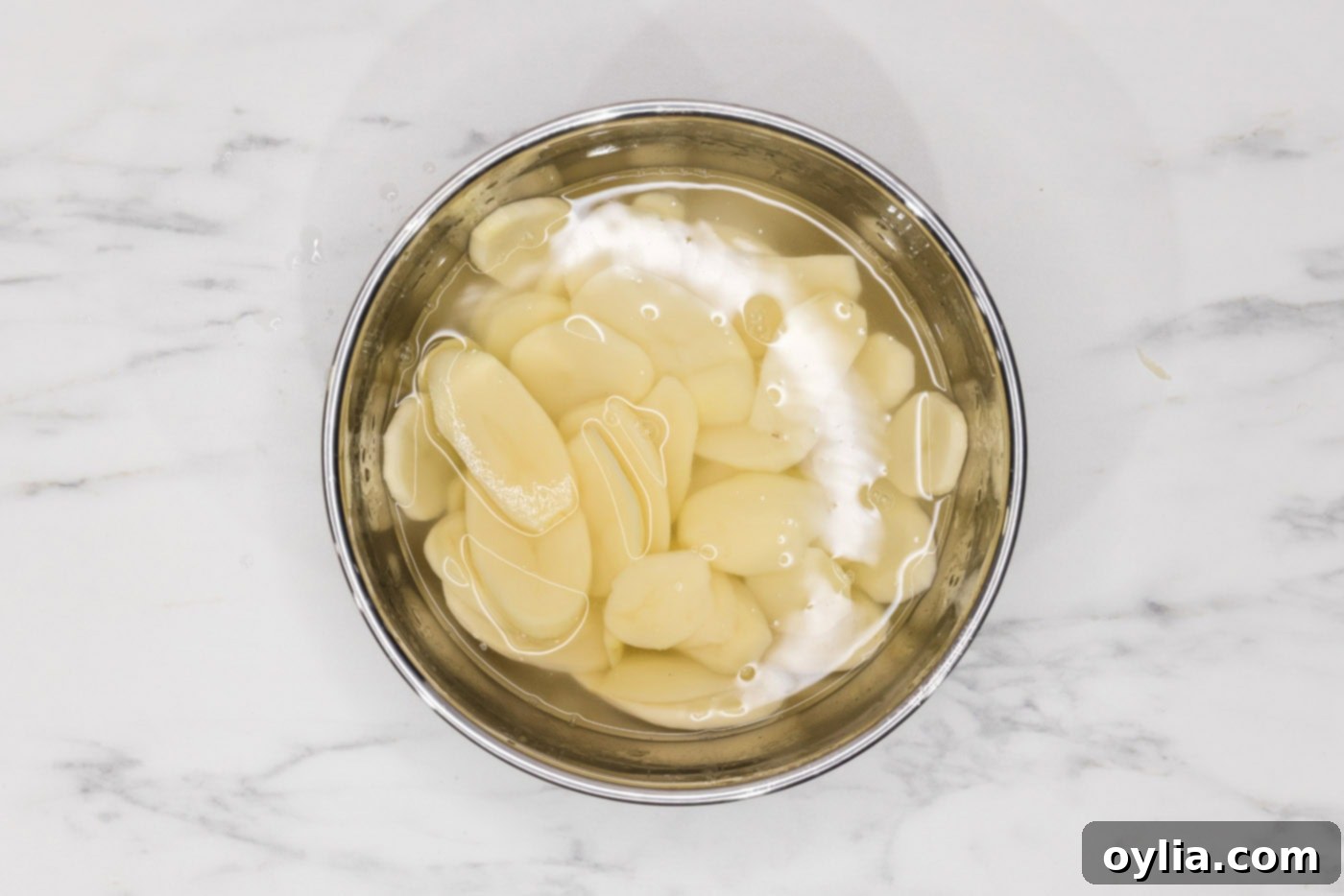 thinly sliced potatoes in a bowl of water