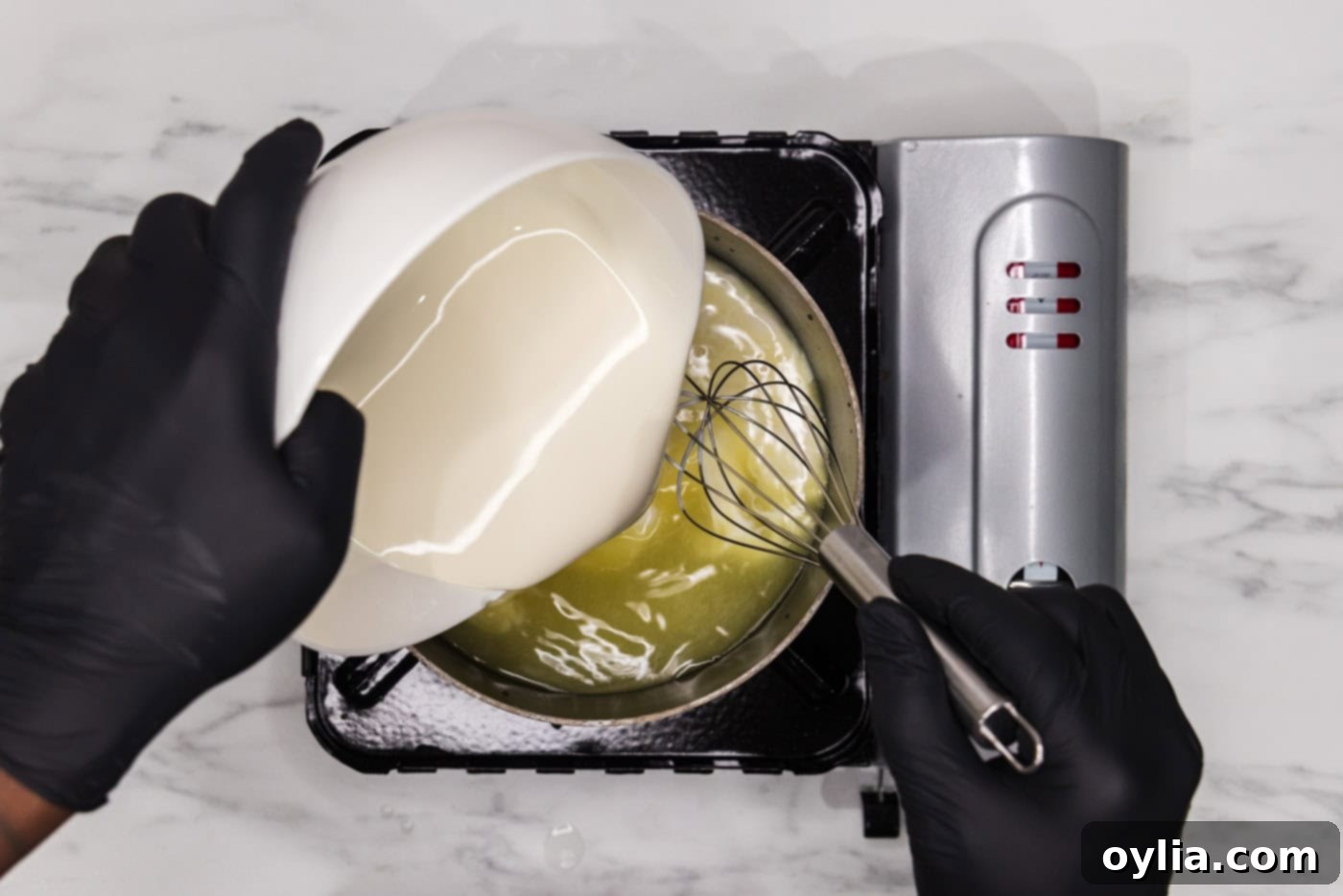 whisking heavy cream into a saucepan with water and chicken base