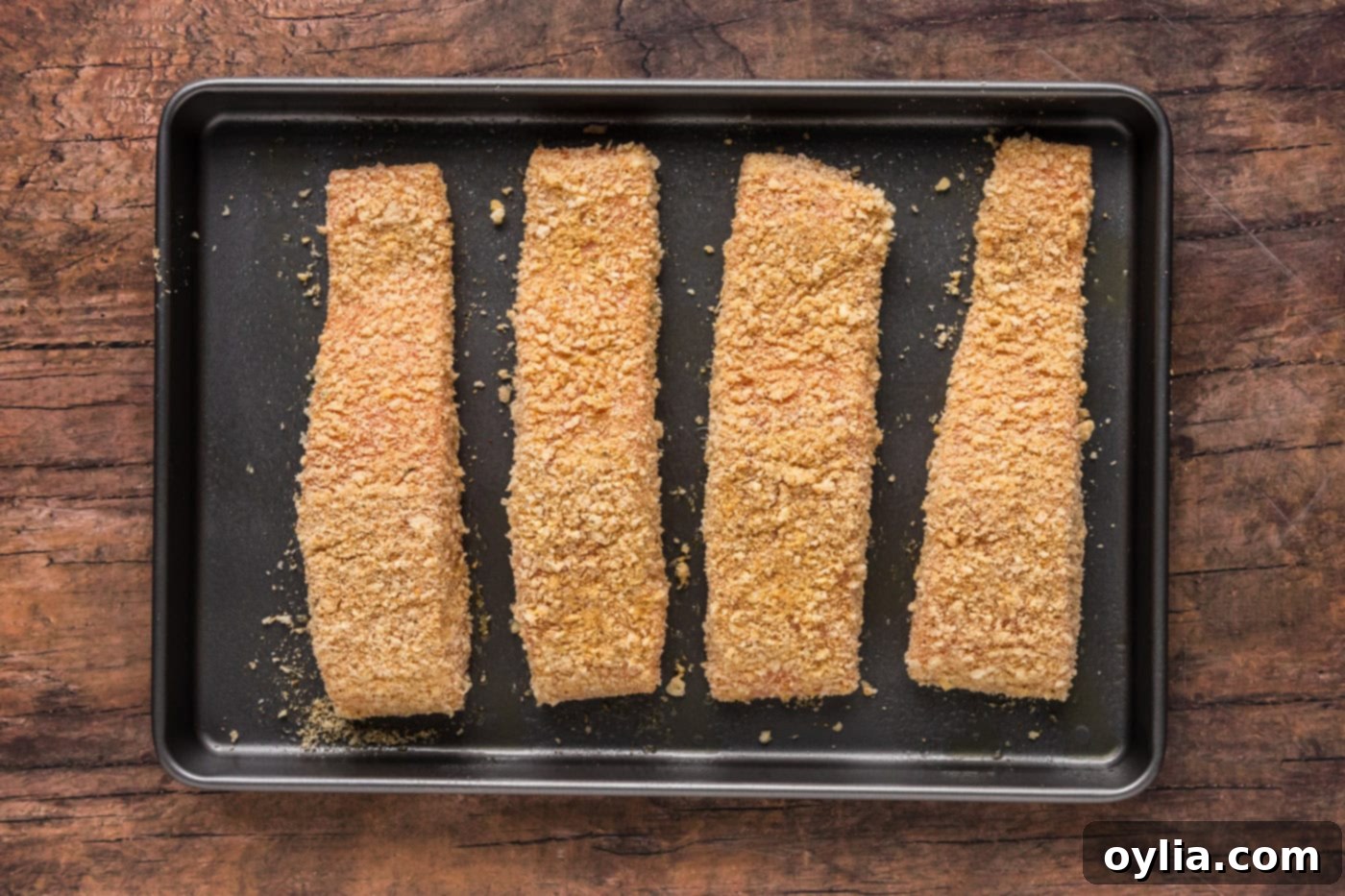 breadcrumb coated salmon filets on a baking sheet