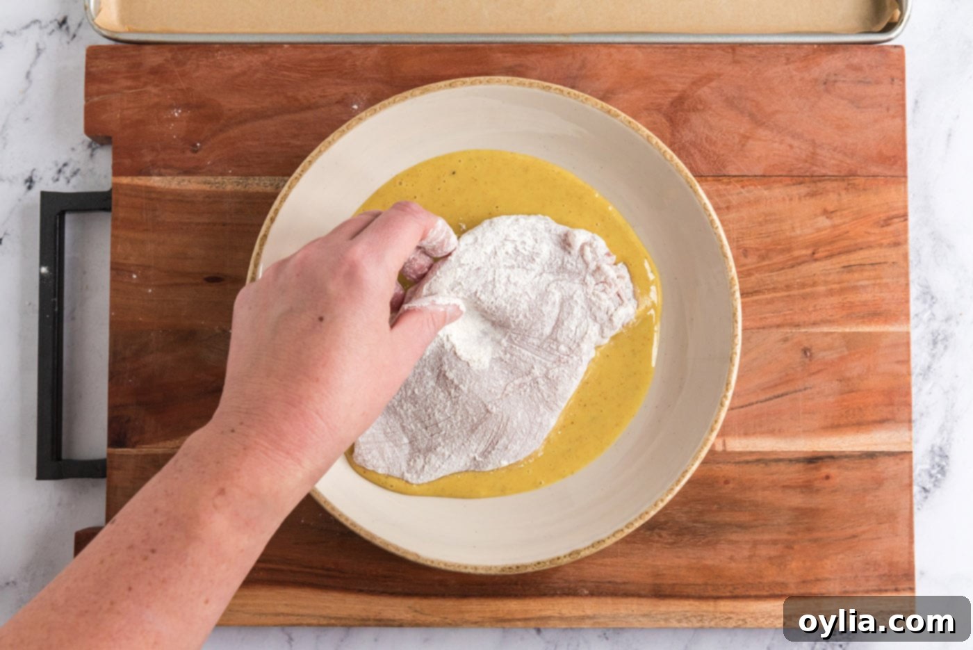 dredging chicken breast in honey mustard dressing, ensuring full coverage