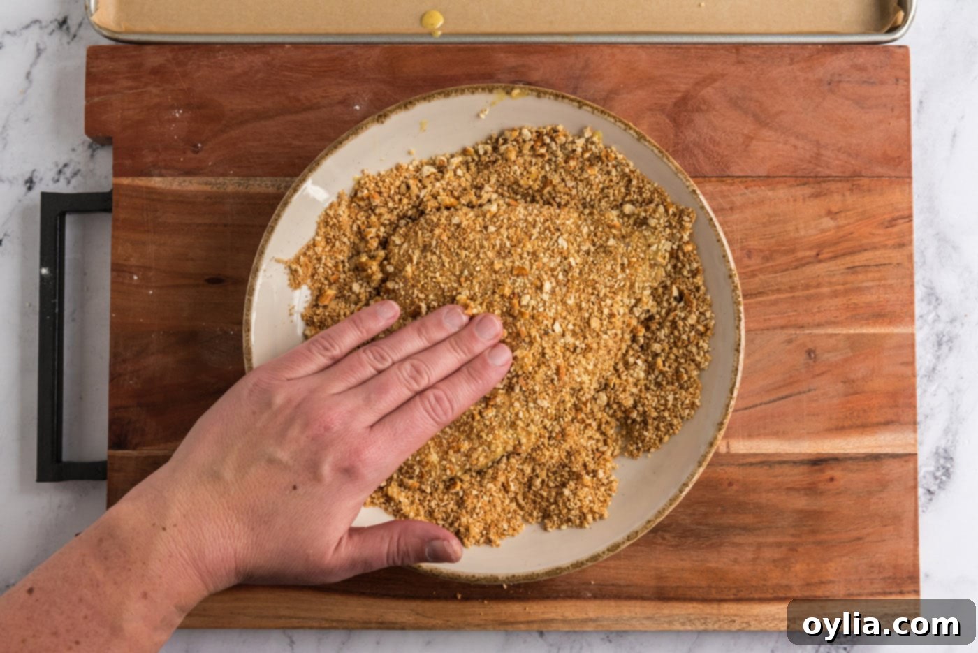 coating honey mustard chicken in crushed pretzel mixture, pressing gently for adherence