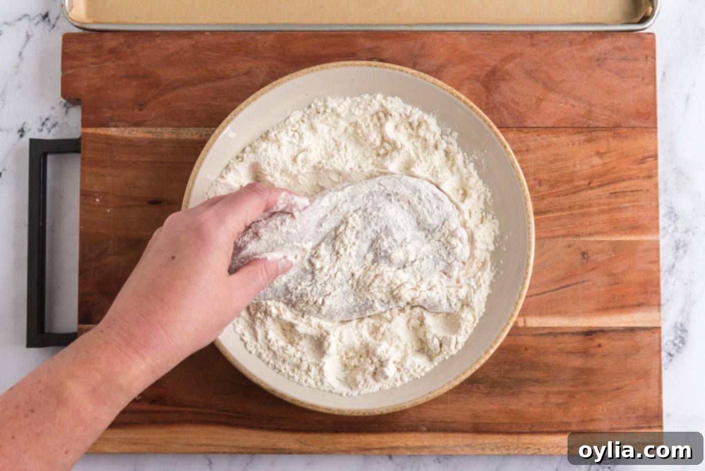dredging chicken breast in flour, the first step for coating