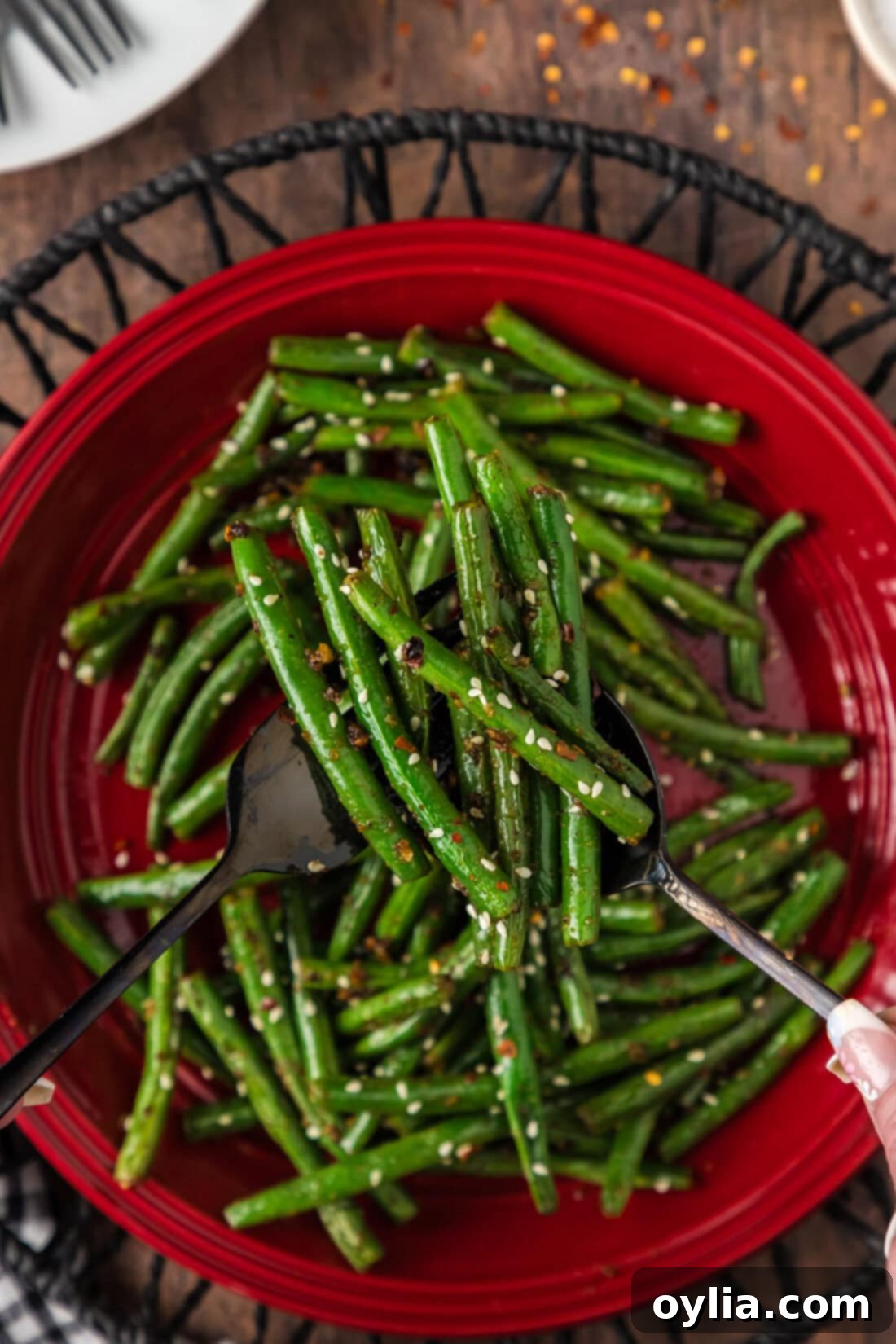 Vibrant Green Bean Sauté 3 Serving utensils holding up Sautéed Green Beans above a plate
