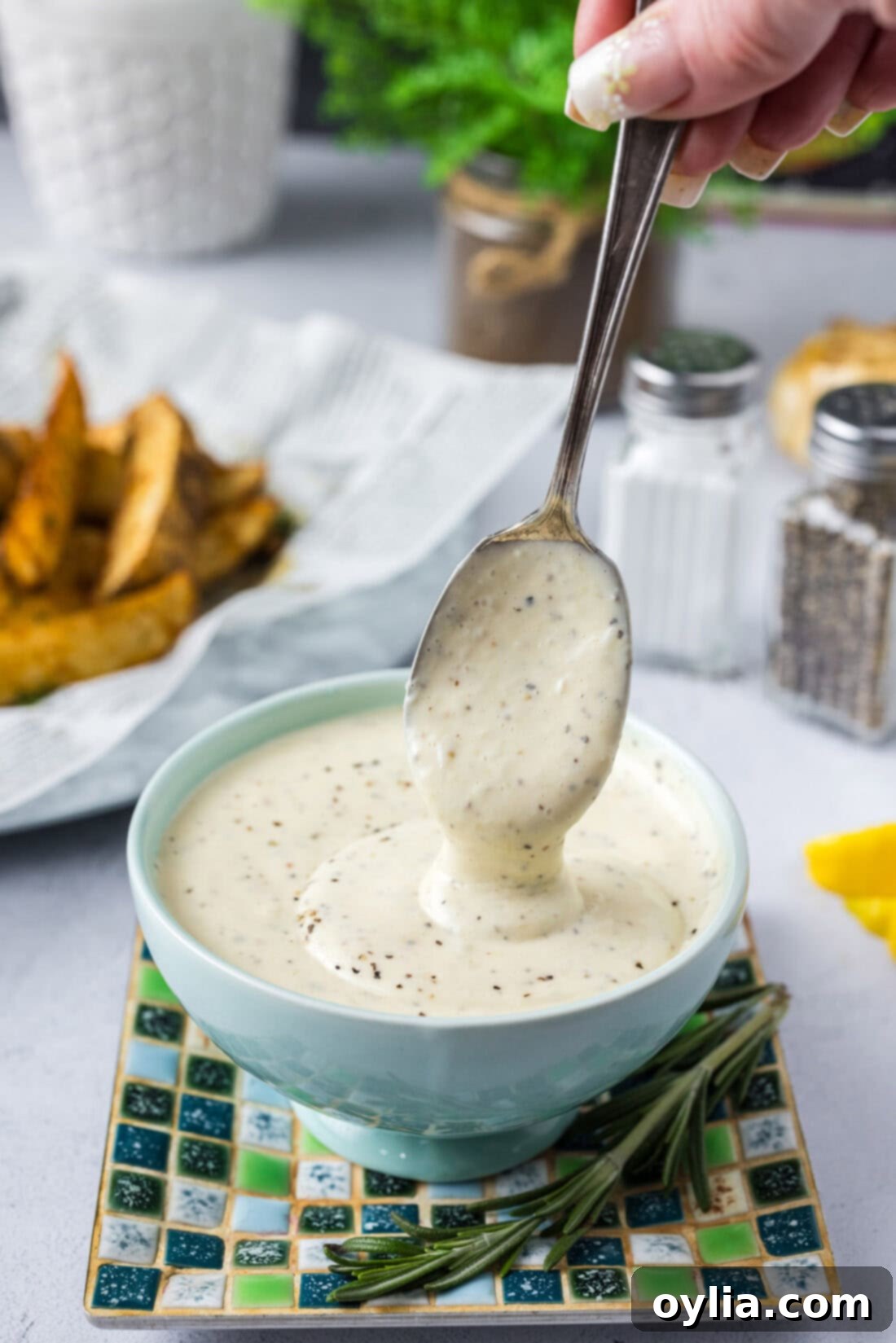 Homemade Garlic Aioli 2 A spoonful of creamy homemade Roasted Garlic Aioli being drizzled into a bowl, highlighting its smooth, rich texture and inviting color.
