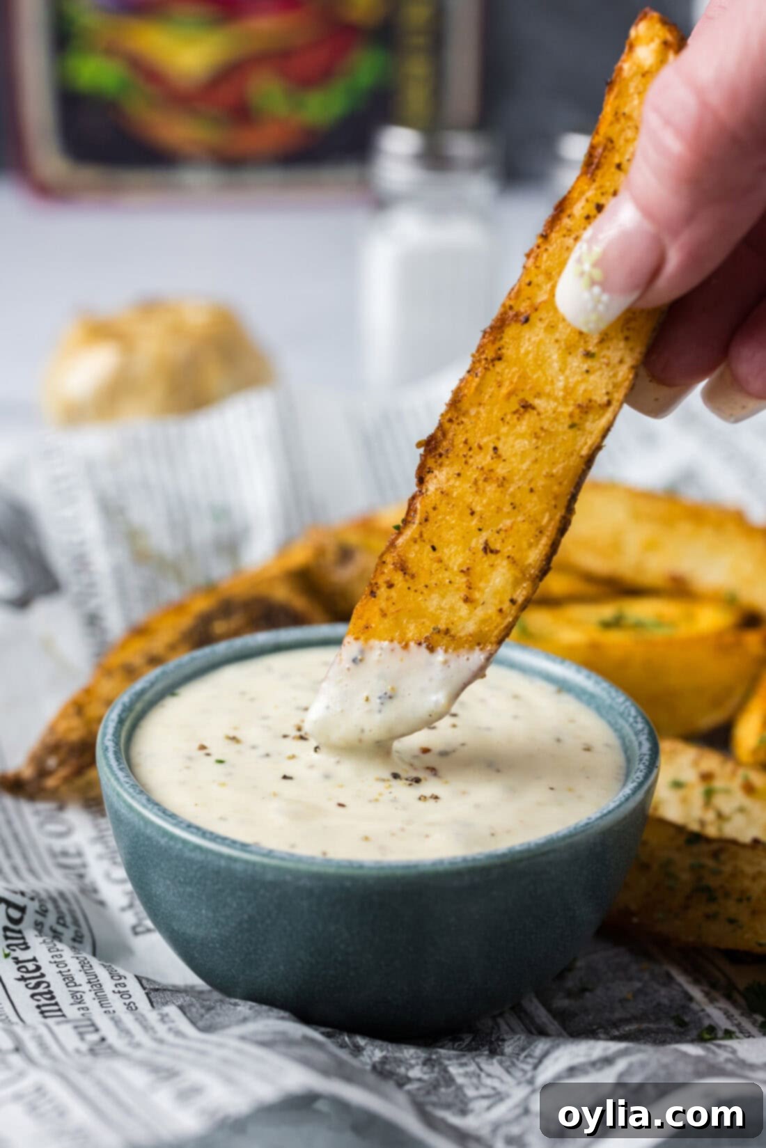 Homemade Garlic Aioli 3 A golden-brown potato wedge being generously dipped into a bowl of creamy homemade Roasted Garlic Aioli.
