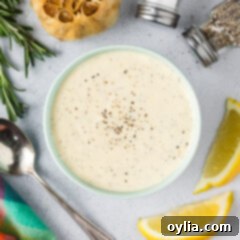 Homemade Garlic Aioli 8 Close up photo of a bowl of homemade creamy Roasted Garlic Aioli, elegantly garnished and surrounded by fresh lemons, whole garlic, and seasonings.