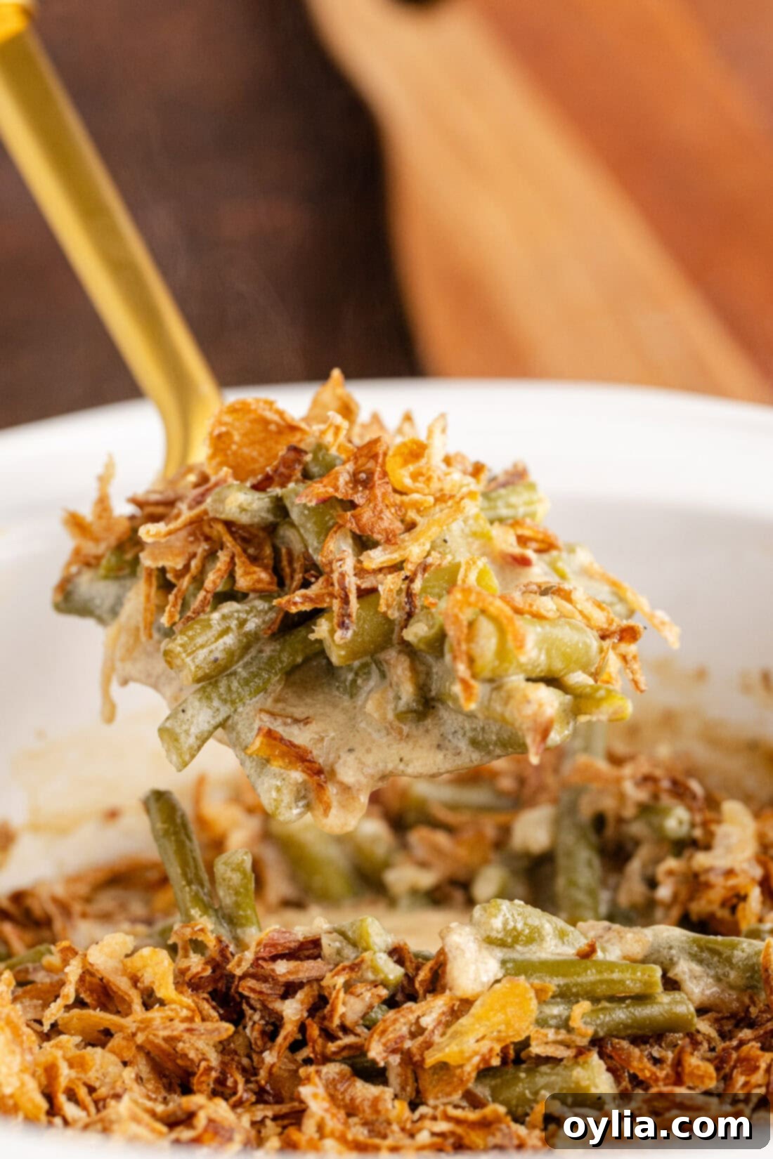 Close up photo of a spoonful of creamy Crockpot Green Bean Casserole with golden fried onions