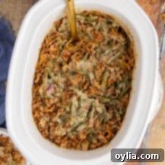 Overhead photo of Creamy Crockpot Green Bean Casserole with a spoon, showing its ready-to-serve texture and crispy onion topping