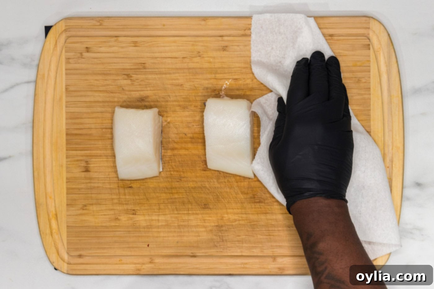 hand patting chilean sea bass dry with paper towels