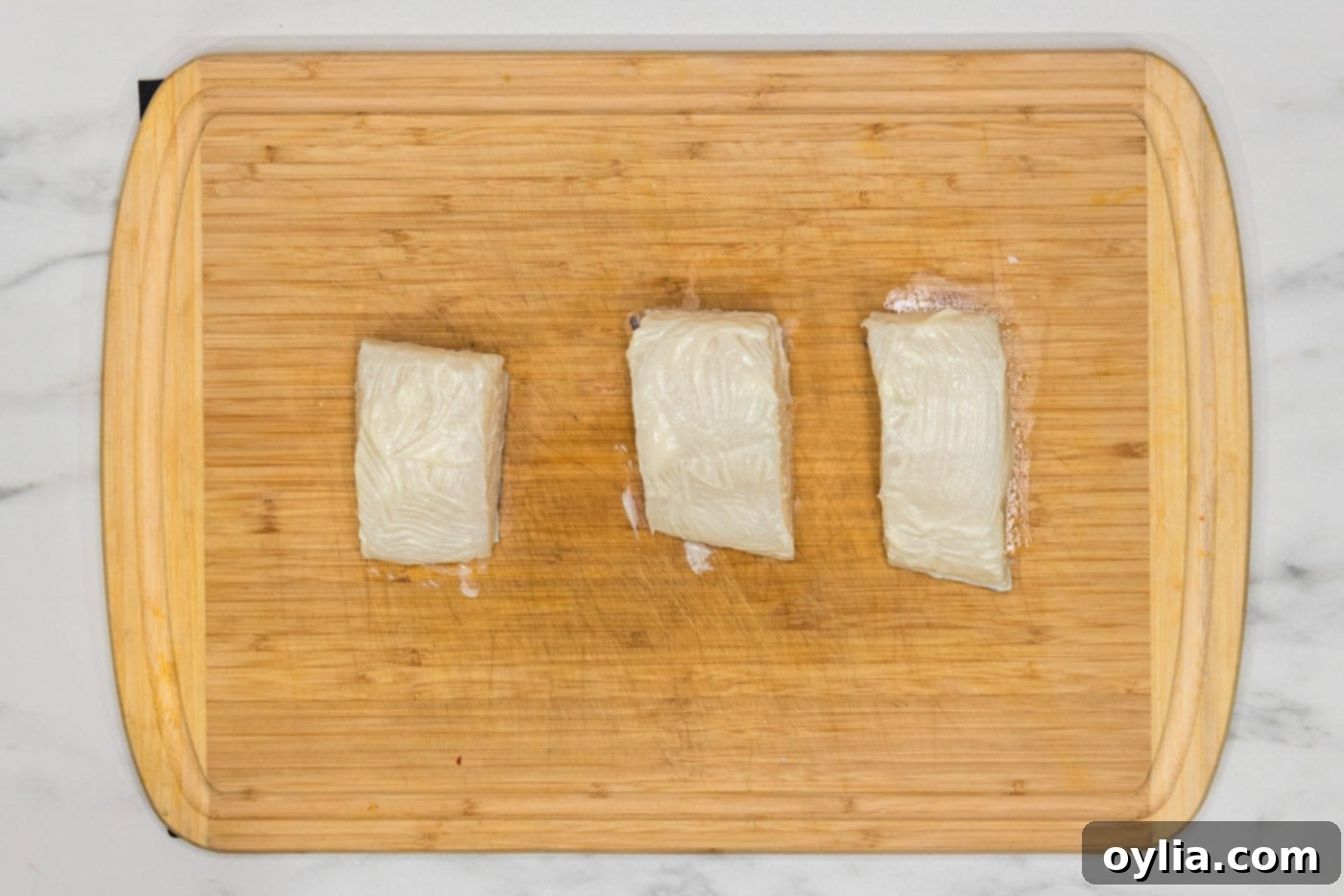 chilean sea bass brushed with butter on a cutting board