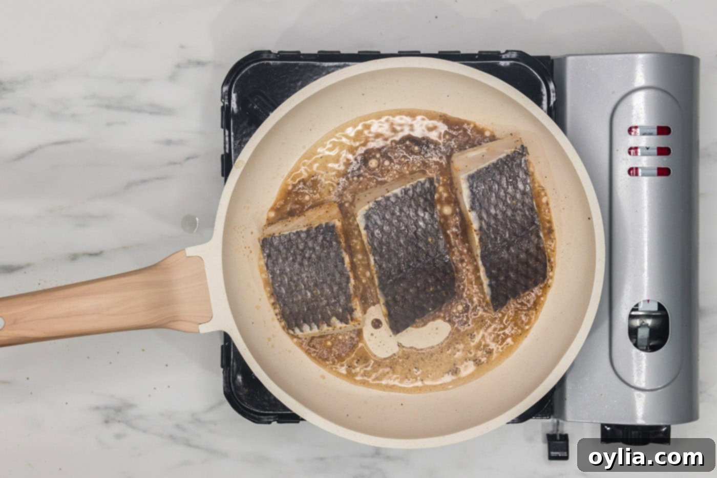 chilean sea bass filets cooking in a skillet skin side up