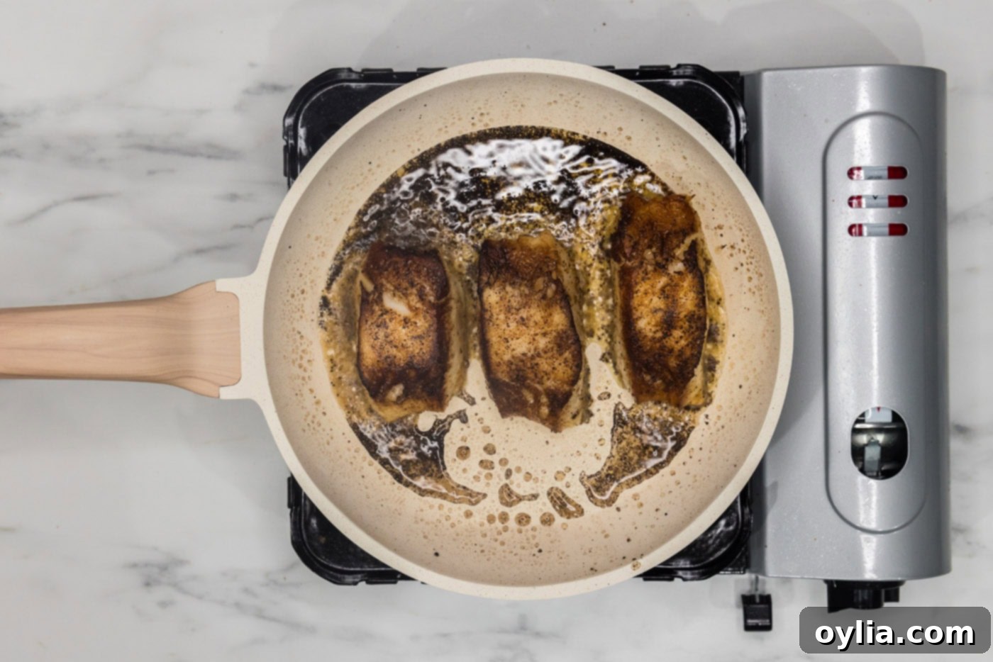 pan seared Chilean sea bass cooking in a skillet