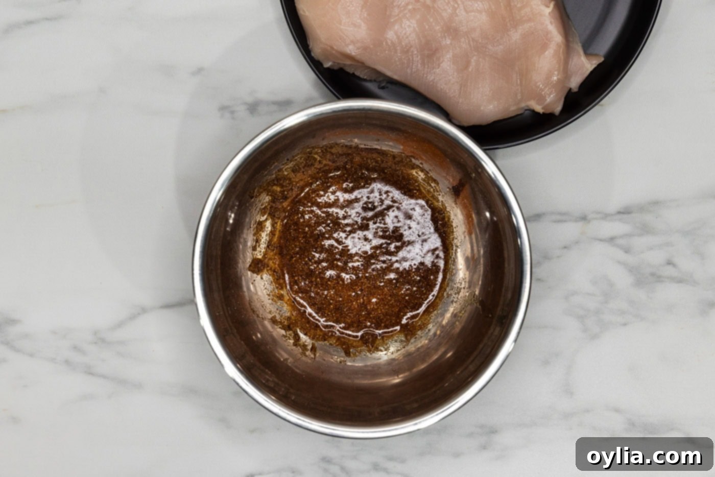 olive oil mixed with spices and seasonings in a bowl ready to be applied to chicken