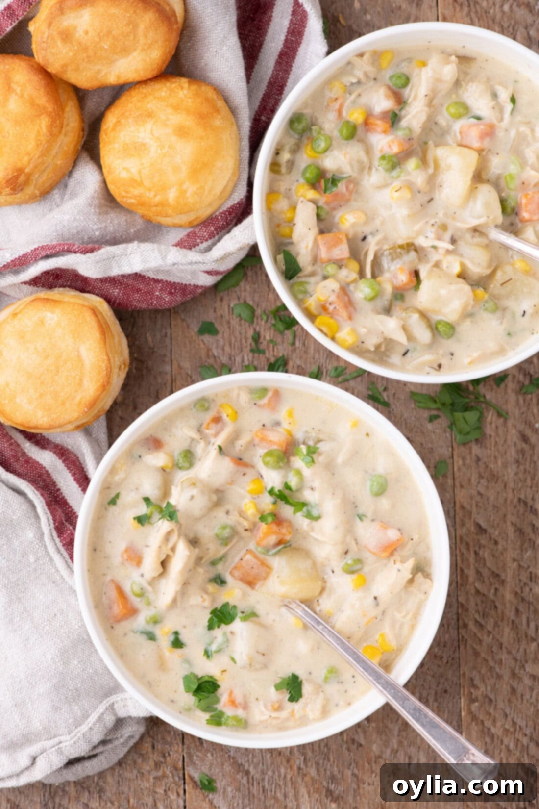 Two bowls of creamy chicken pot pie soup with biscuits on the side, ready to be enjoyed.