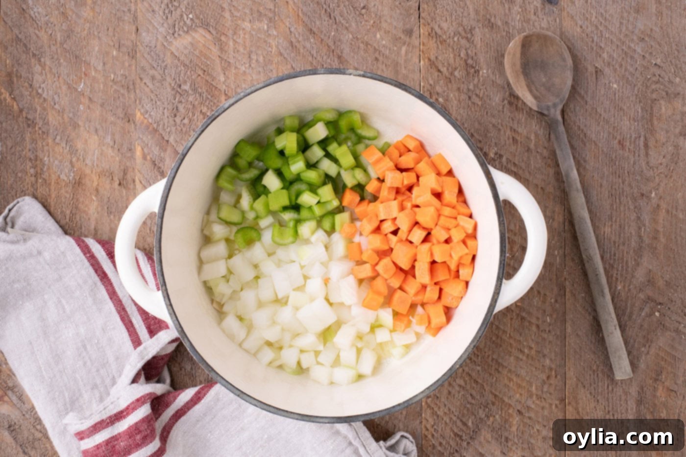 Sautéing diced onions, carrots, and celery in melted butter in a Dutch oven, softening for the soup base.