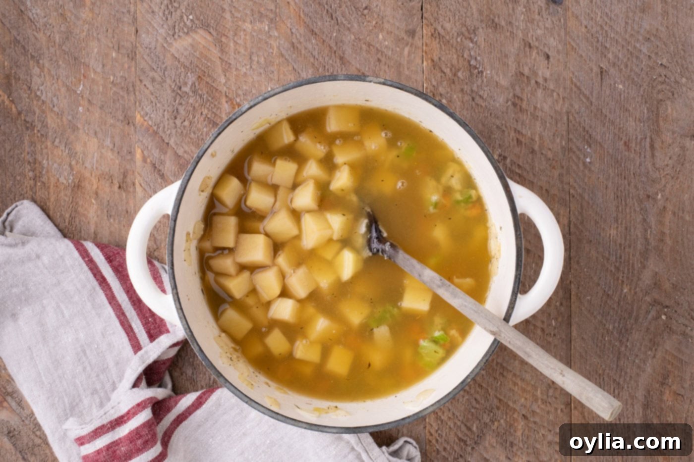 Diced potatoes and chicken broth added to the Dutch oven with the sautéed vegetables, ready to simmer.