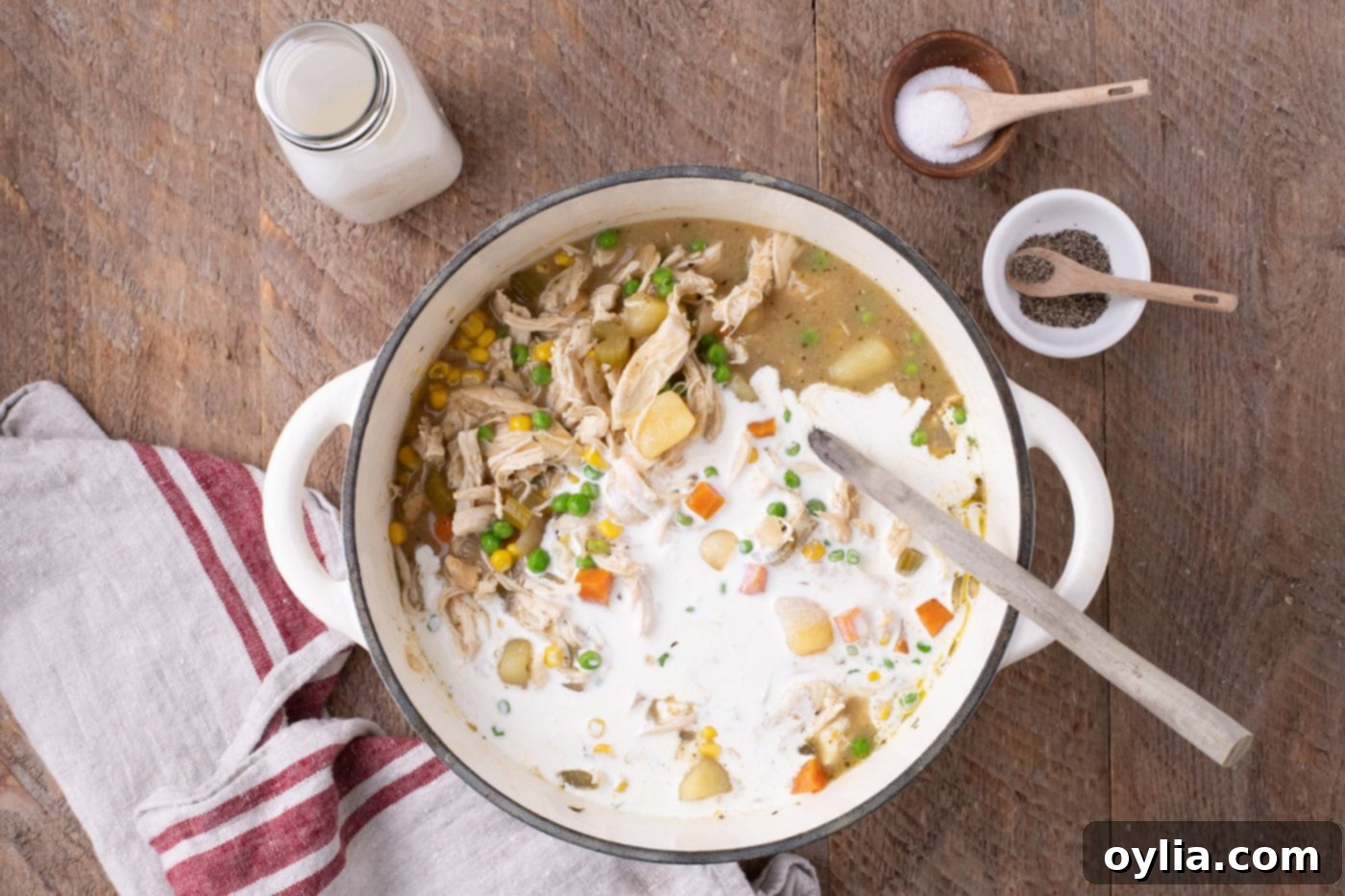 Pouring heavy cream into the chicken pot pie soup to create a rich and creamy texture.