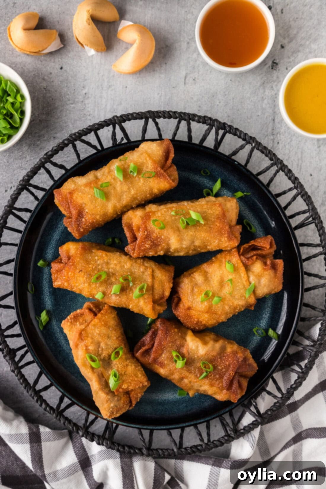 A close-up shot of a plate brimming with golden-brown, perfectly fried homemade shrimp egg rolls, garnished for serving