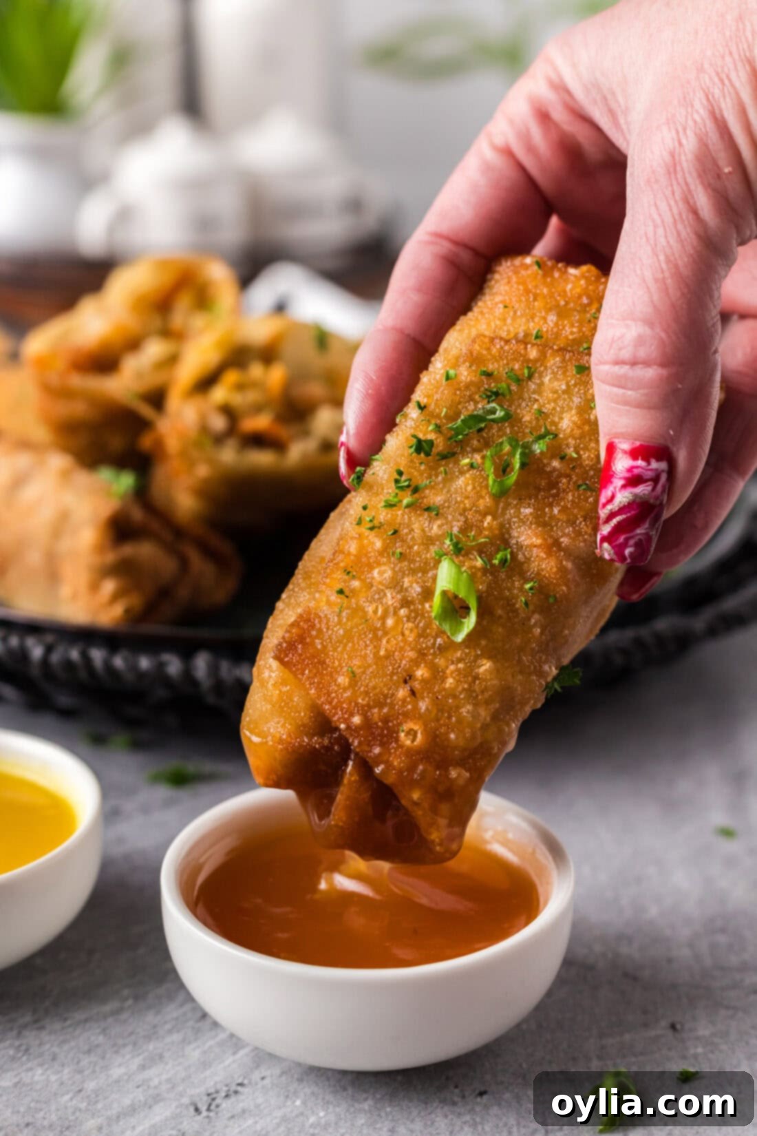 Crispy shrimp egg roll being dipped into a sweet and sour sauce, highlighting its golden crust