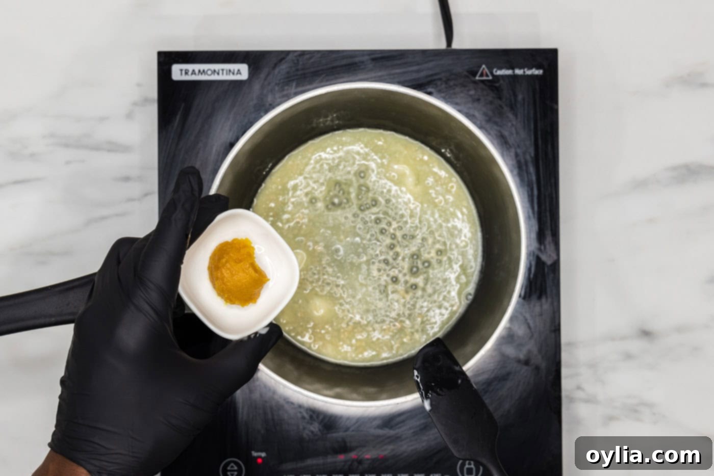 hand holding chicken base over melted butter in a saucepan