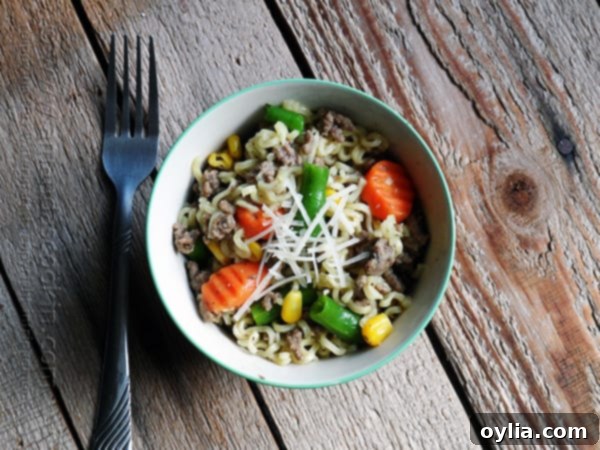 An overhead photo of a vibrant ramen noodle and beef skillet with mixed vegetables in a blue and white bowl, ready to be served.