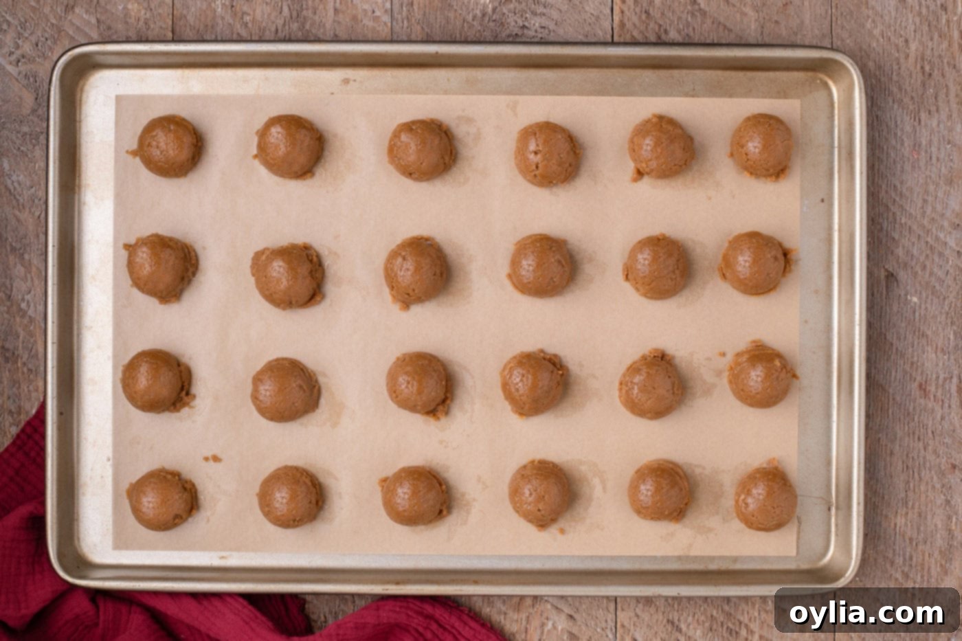 Scooped and rolled gingerbread Oreo balls freezing on a parchment-lined baking sheet