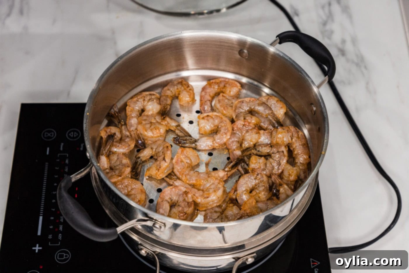 Seasoned raw shrimp arranged in a steamer pot basket, ready for cooking