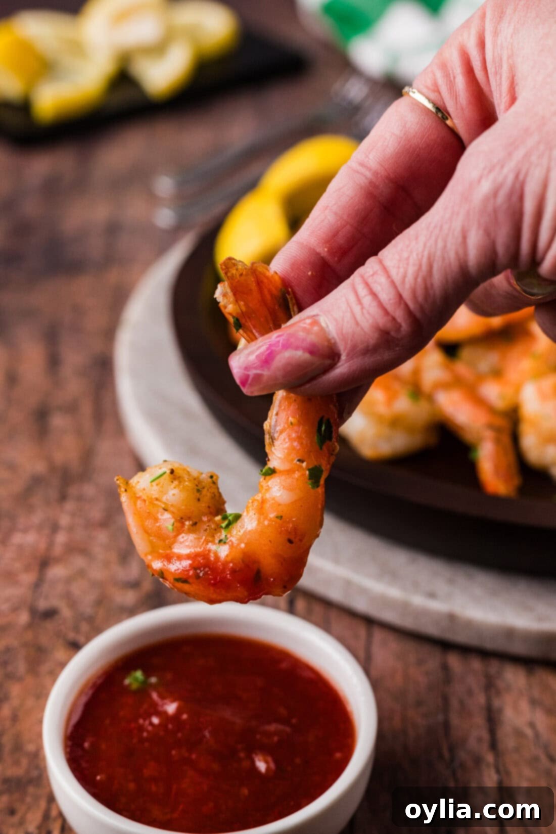 Succulent Steamed Shrimp 8 Hand holding a perfectly steamed shrimp, ready to be dipped into a bowl of zesty cocktail sauce