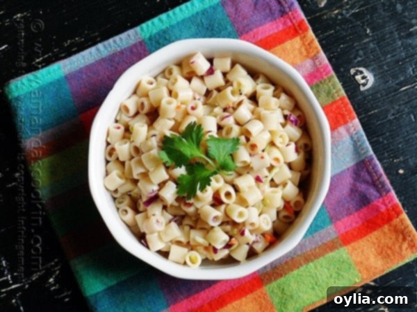 An overhead photo of vibrant 3-ingredient quick pasta salad in a white bowl with fresh parsley on top, perfect for summer gatherings.