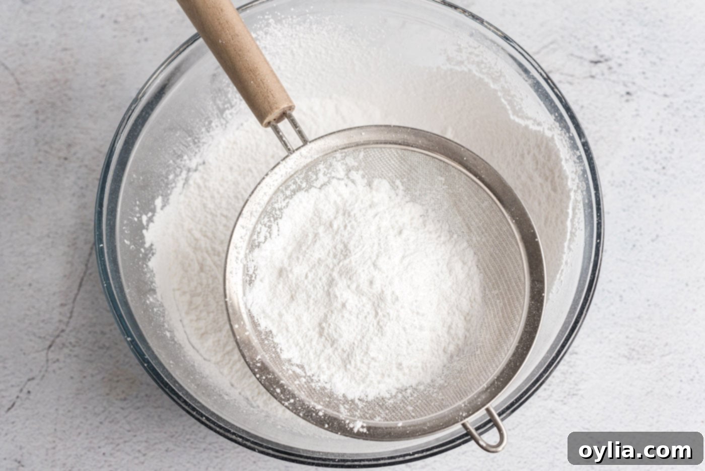 Sifting powdered sugar into a bowl for the frosting