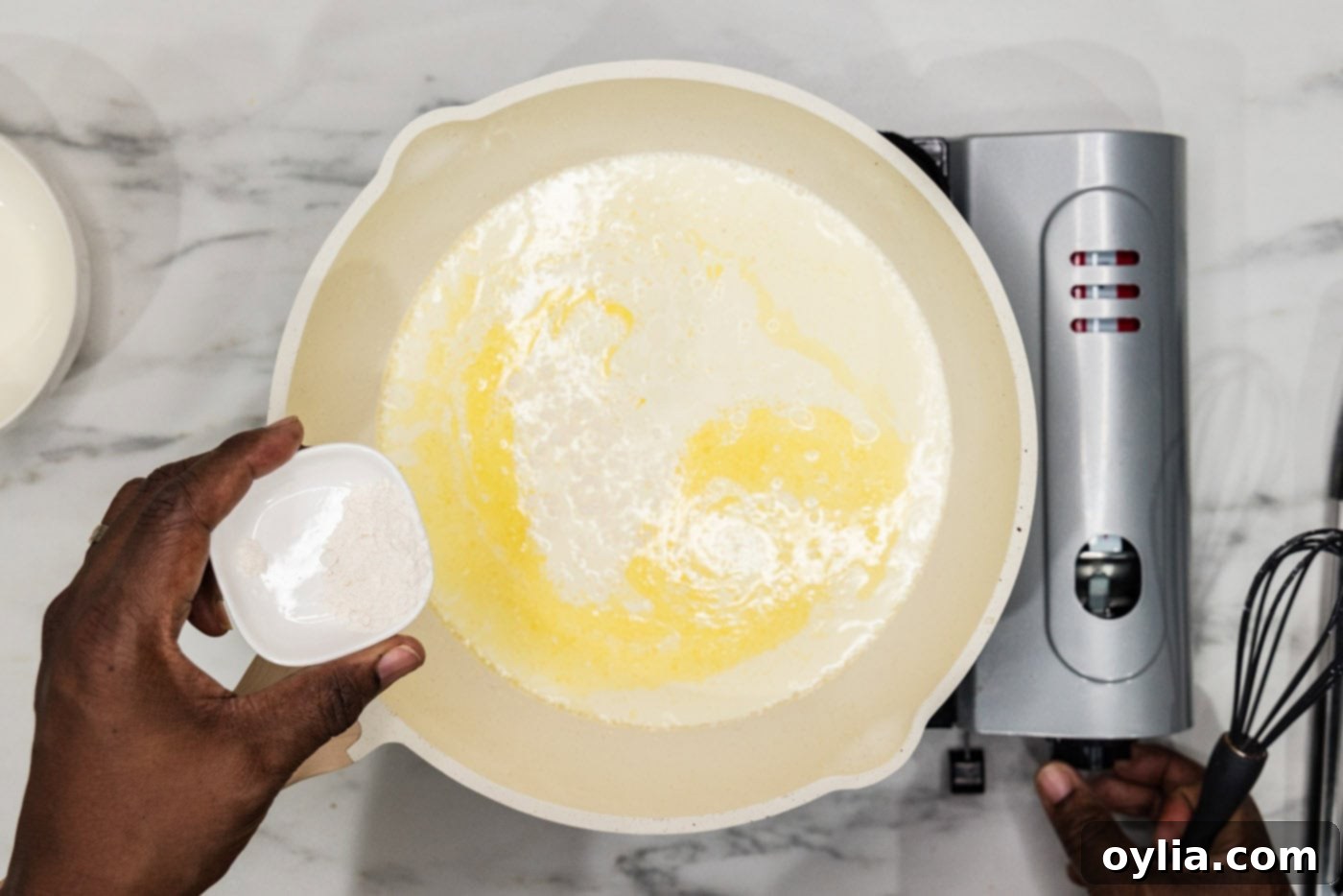 adding flour to skillet of half and half and butter