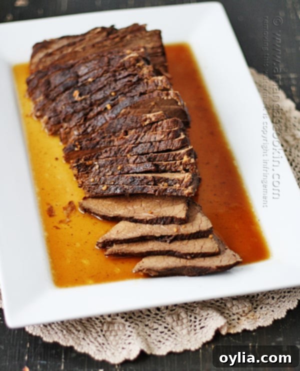 An overhead photo of sliced slow cooker roast with brandy sauce on a white platter.
