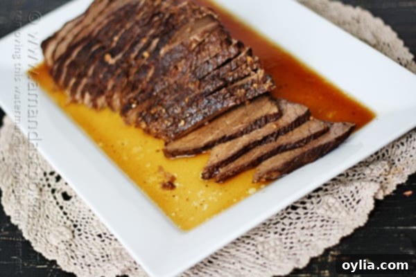 A close up of sliced slow cooker roast with brandy sauce on a white platter.