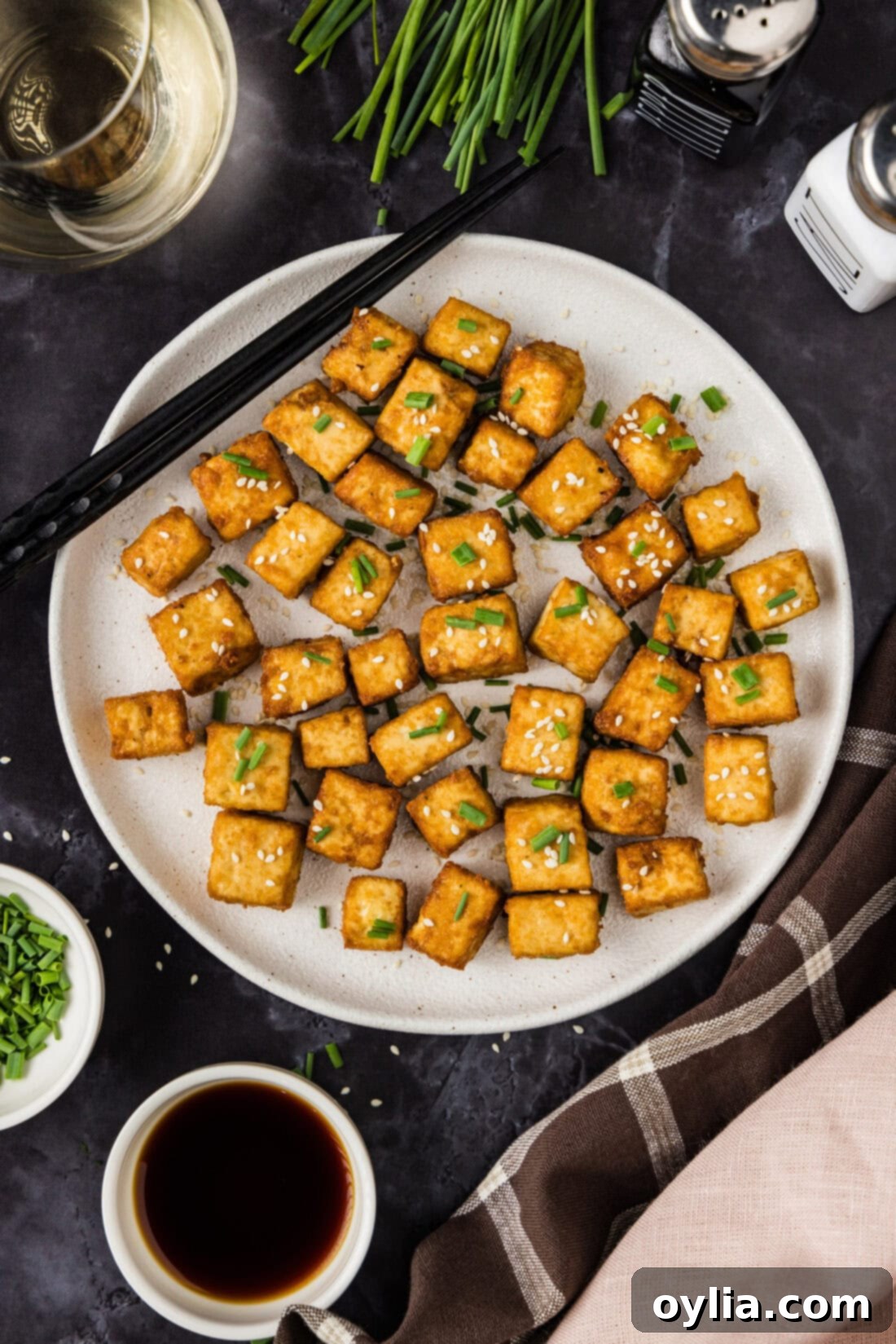 Plate of crispy deep-fried tofu cubes with chopsticks resting, seasoned with umami soy sauce.
