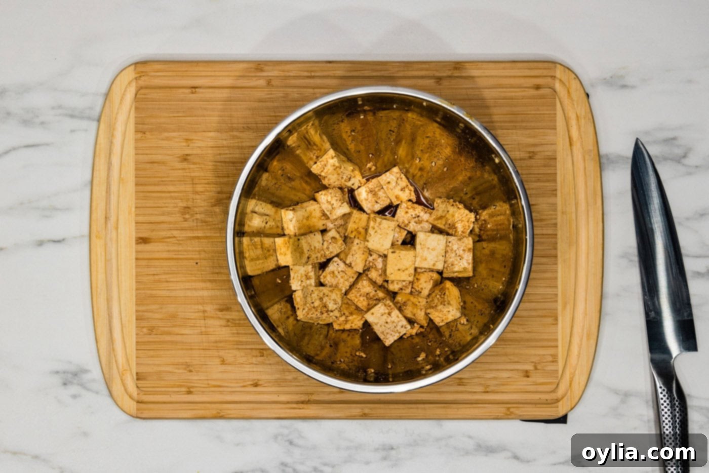 Tofu cubes seasoned with soy sauce, garlic salt, and black pepper, being tossed in a mixing bowl.