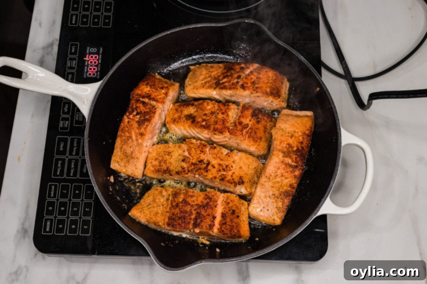 Pan-seared salmon fillets cooking in a hot skillet, developing a golden crust.