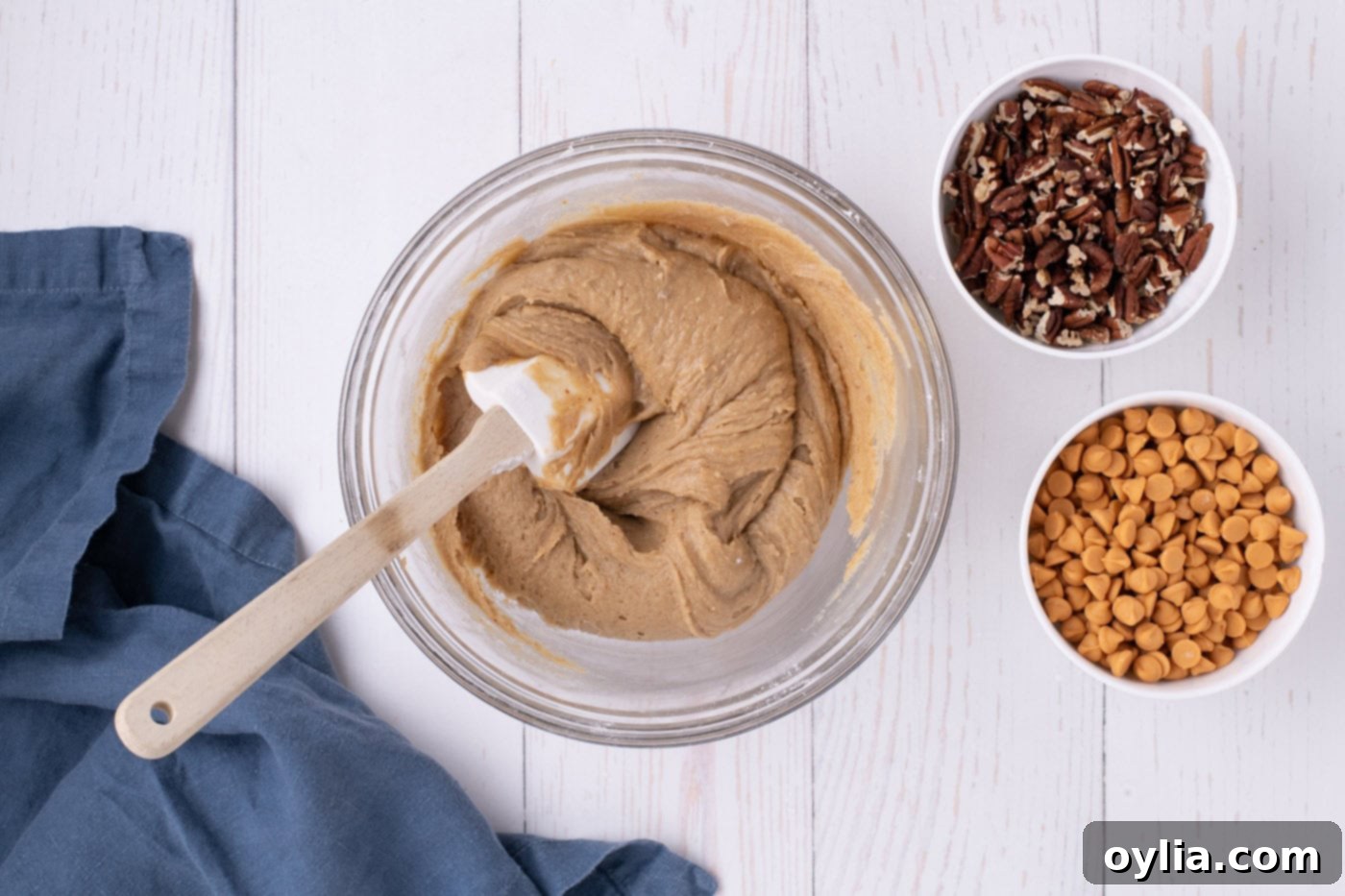 Smooth blondies batter in a mixing bowl being gently stirred with a rubber spatula