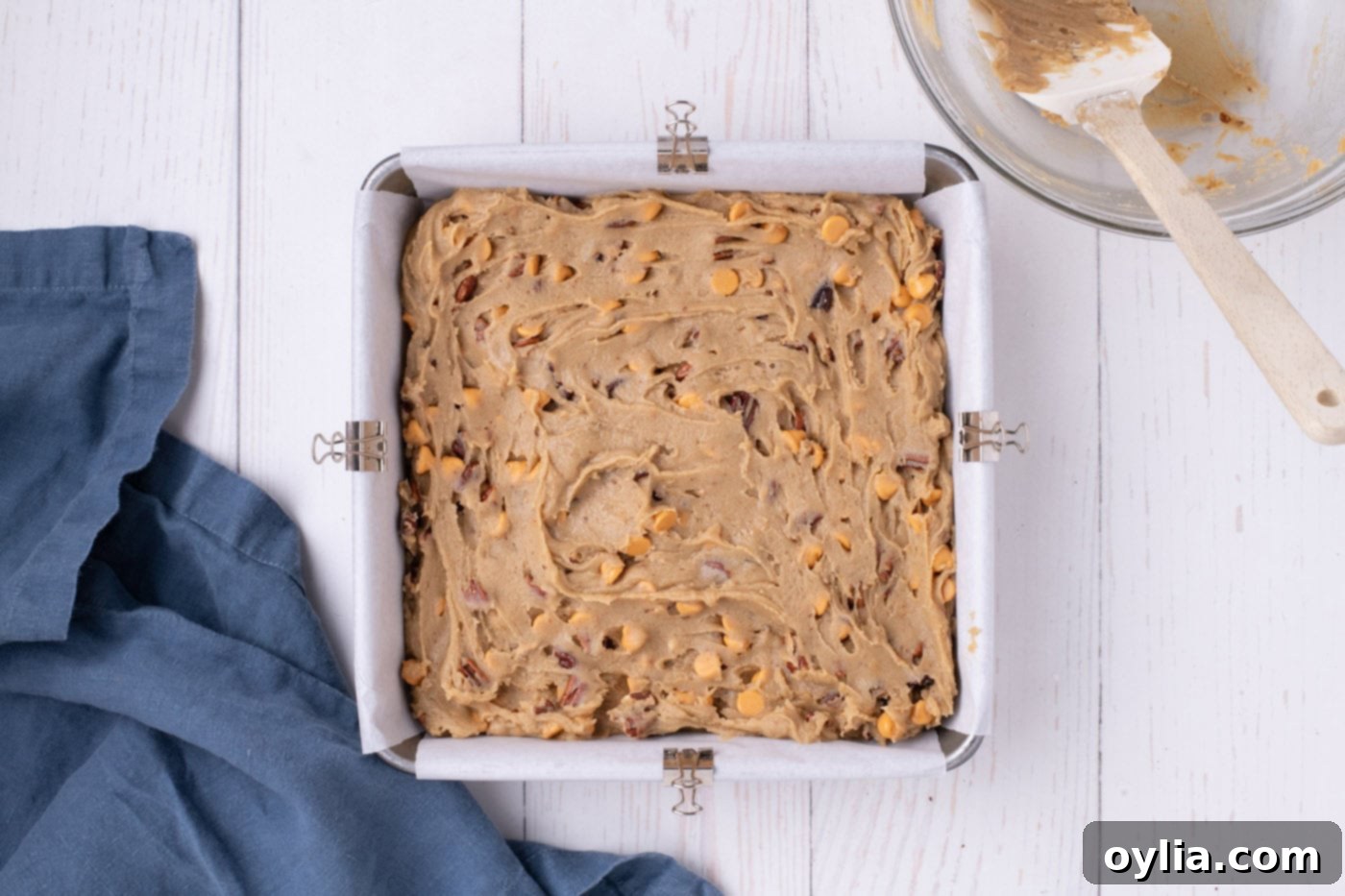 Smooth butterscotch brownie batter evenly spread in a parchment-lined baking pan, ready for baking