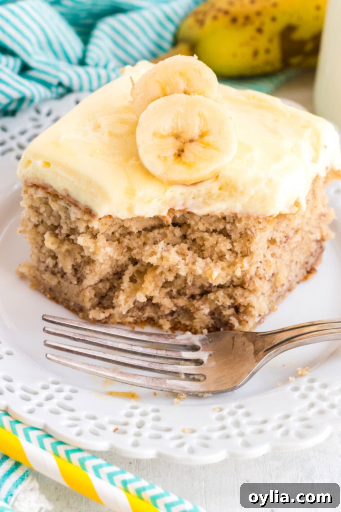A delectable slice of moist banana cake with a bite taken out, showcasing the creamy banana-flavored whipped cream frosting.