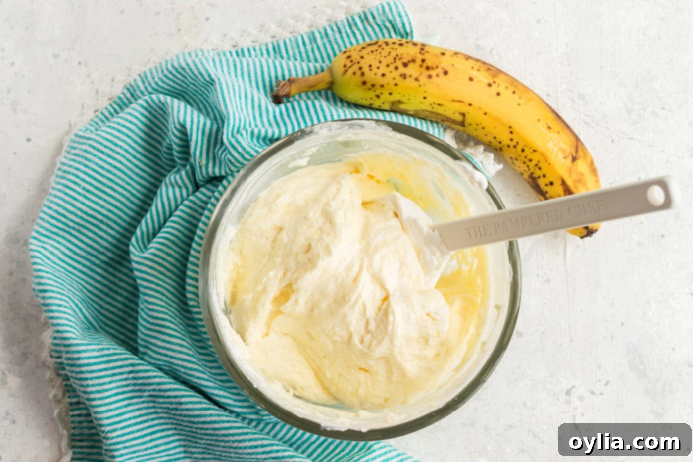 A bowl of freshly made, light and airy banana-flavored whipped cream frosting, ready to be spread onto the cooled cake.