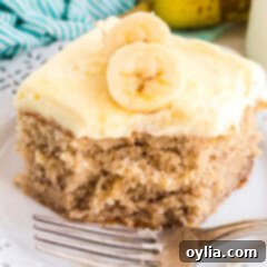 A beautiful slice of banana cake topped with creamy whipped frosting, ready to be enjoyed.