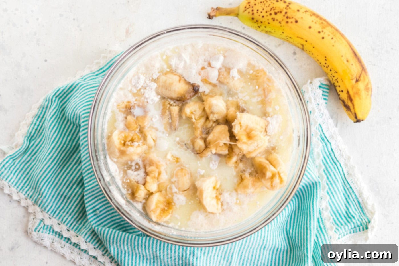 Mashed or chunked ripe bananas added to the mixing bowl along with milk, eggs, and oil, completing the wet ingredients for the cake batter.