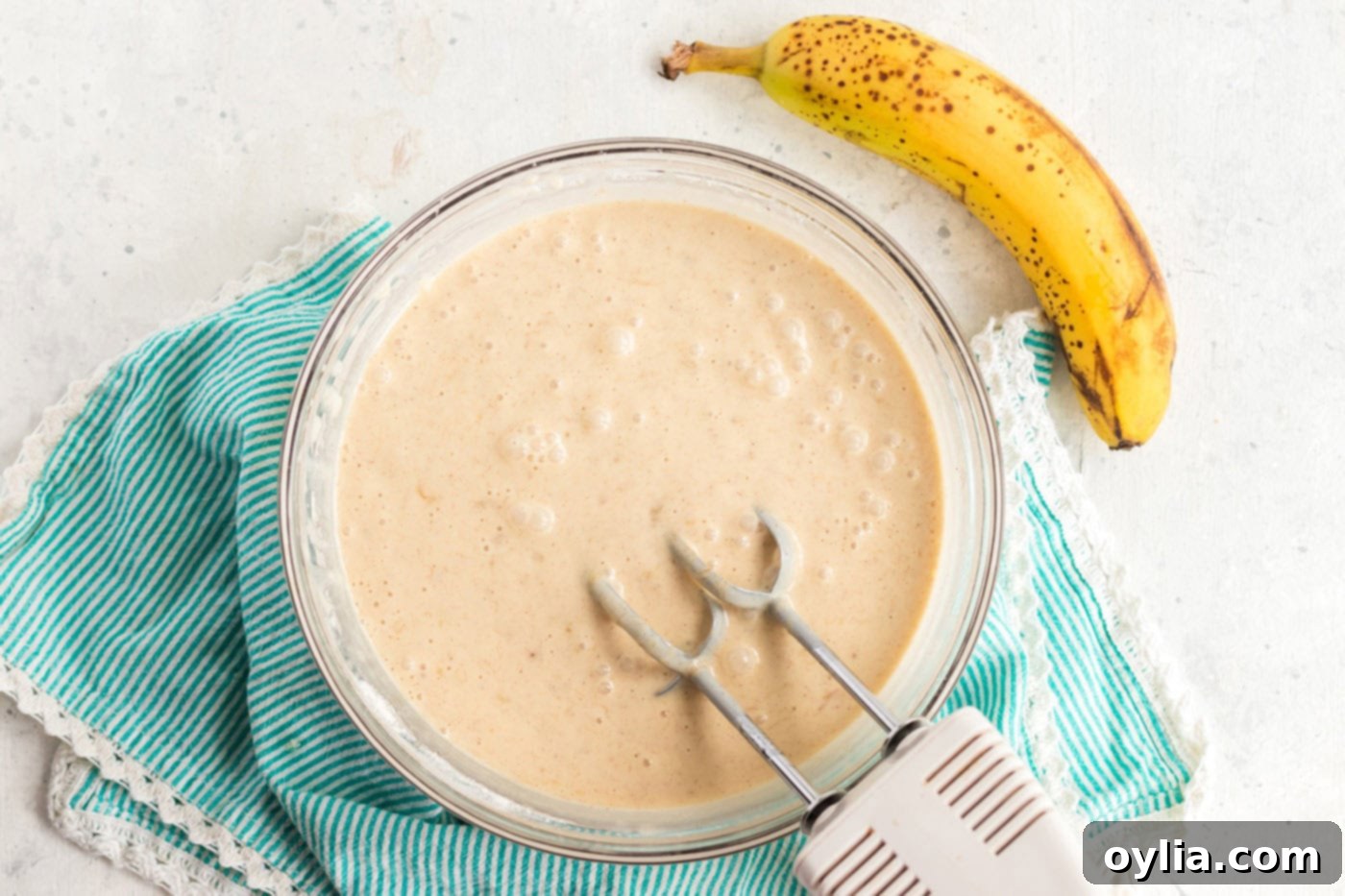 Smooth, well-blended banana cake batter in a mixing bowl after two minutes of beating on medium-high speed.