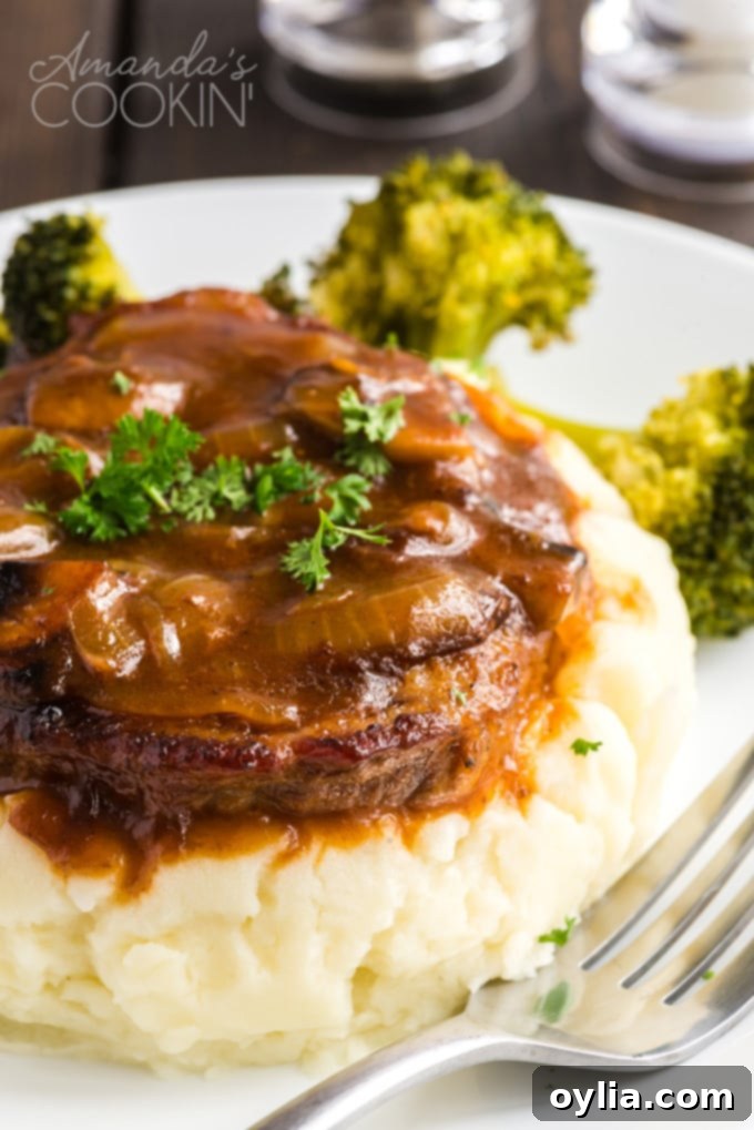 Swiss steak and gravy served on a bed of creamy mashed potatoes, ready to be enjoyed.