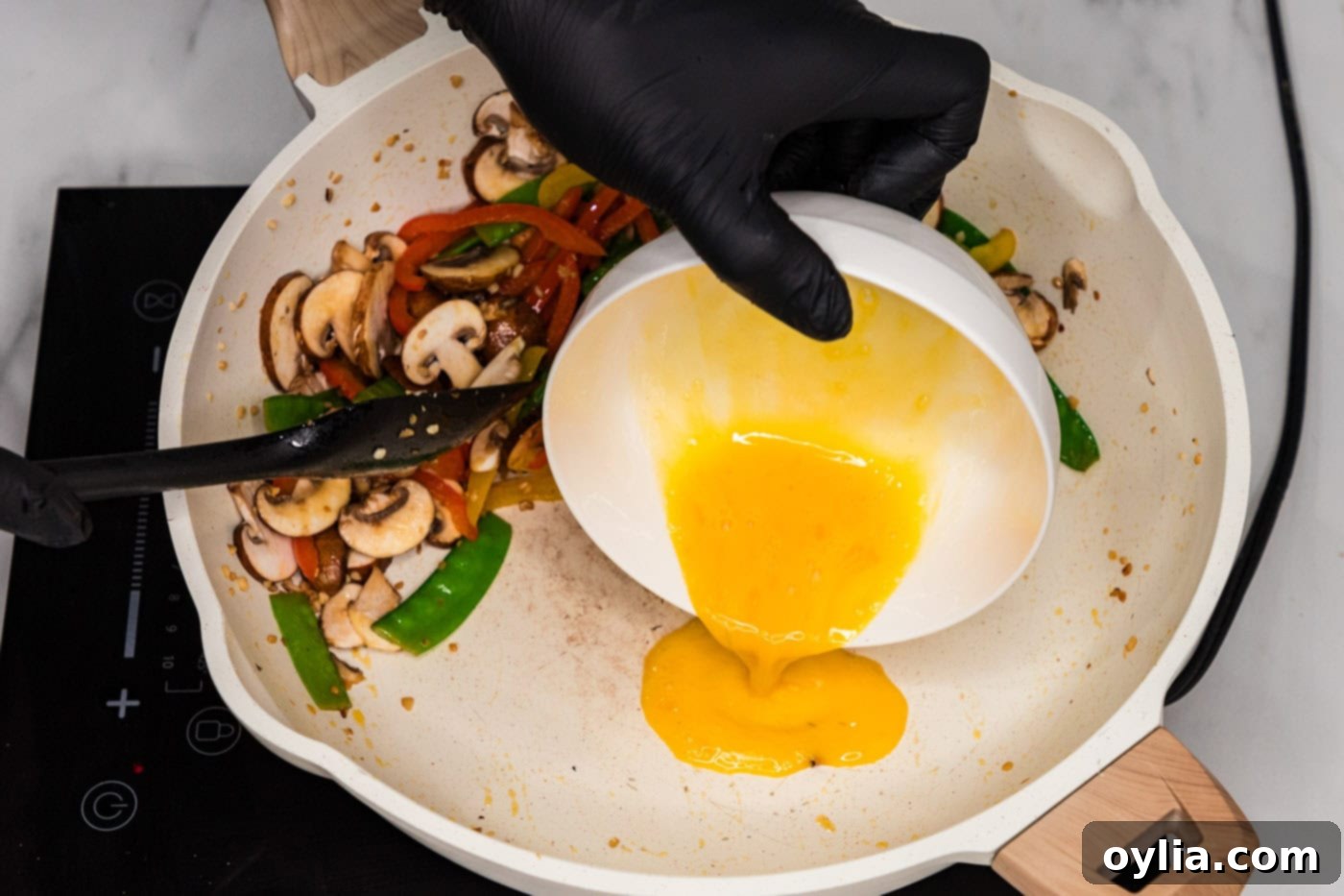 pouring egg into skillet with vegetables
